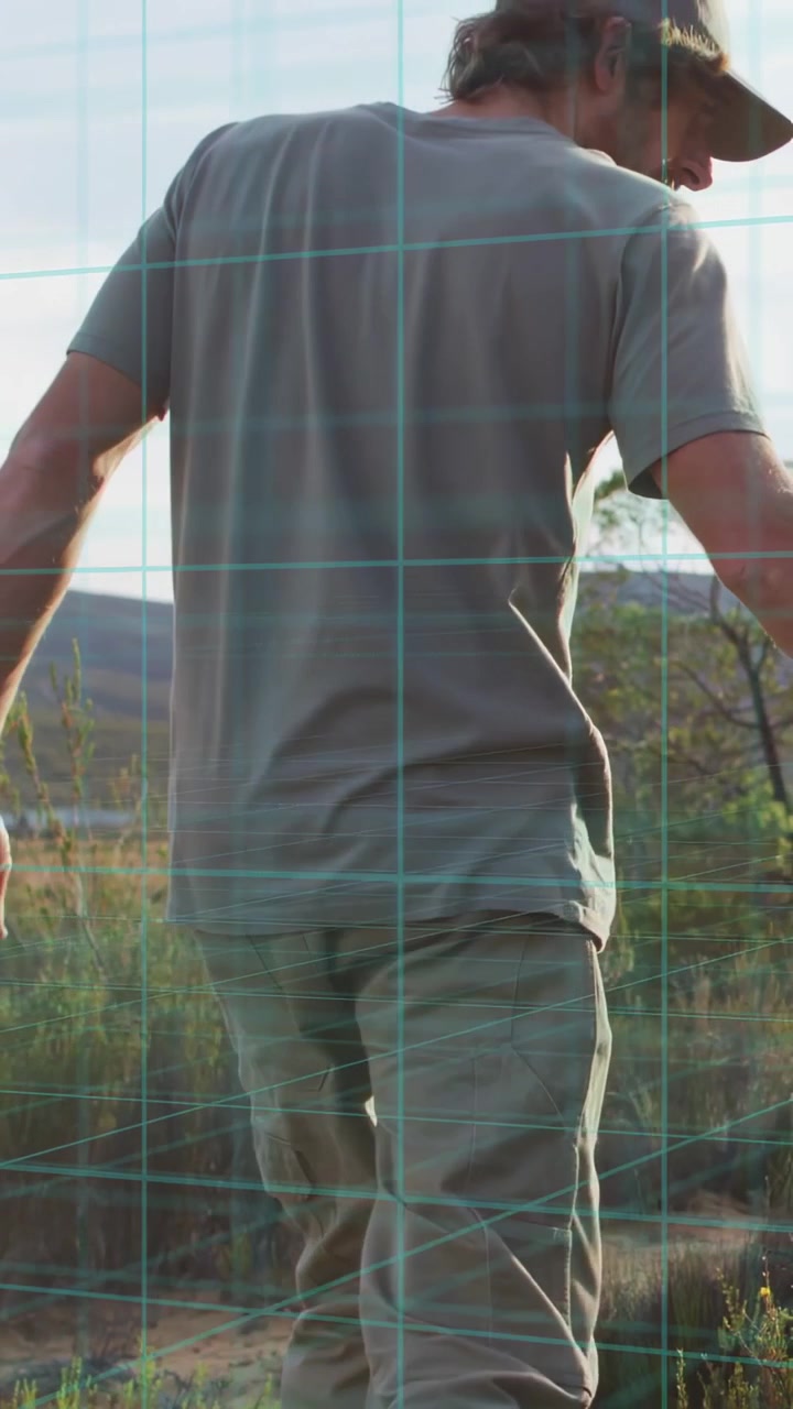 Vertical video: Adult man walking trail, camera pulling back revealing cap, teal grid mapping tech
