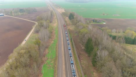 Cargo-train-riding-in-rural-area-on-foggy-day,-aerial-view