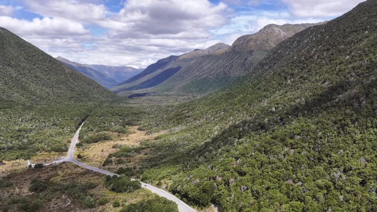 Riprese aeree con drone di una valle profonda e stretta con una fitta foresta verde e un fiume serpeggiante nel Parco Nazionale di Fiordland, Isola del Sud della Nuova Zelanda.