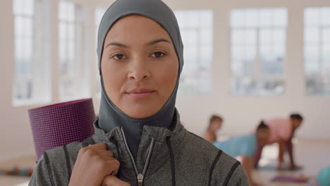 yoga class portrait of happy muslim woman smiling confidently wearing hijab headscarf enjoying healthy lifestyle with multi ethnic people practicing in fitness studio background