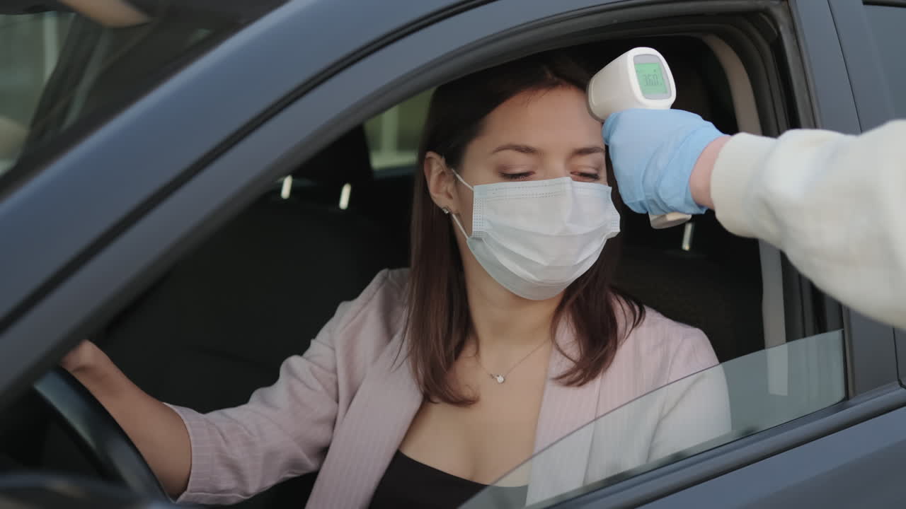 여자 가 차 에서 온도 를 측정 하고 있다