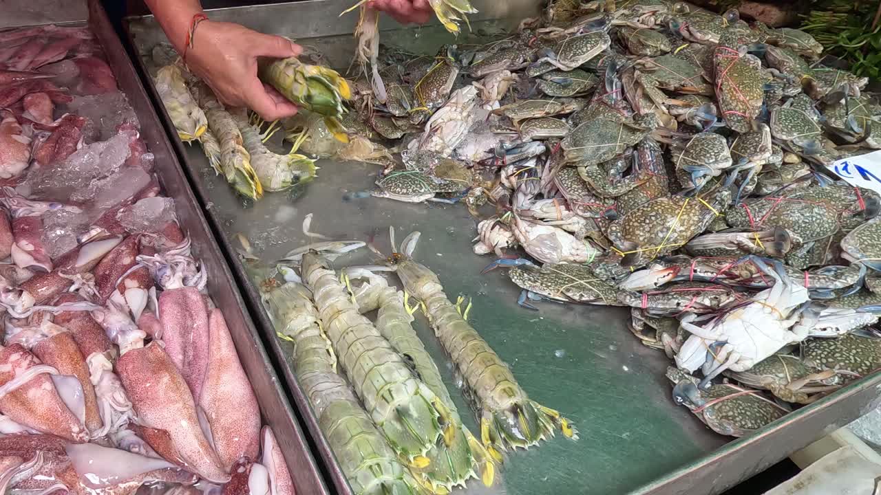 전시 를 위해 얼음 에 여러 가지 해산물 을 배열 하는 사람