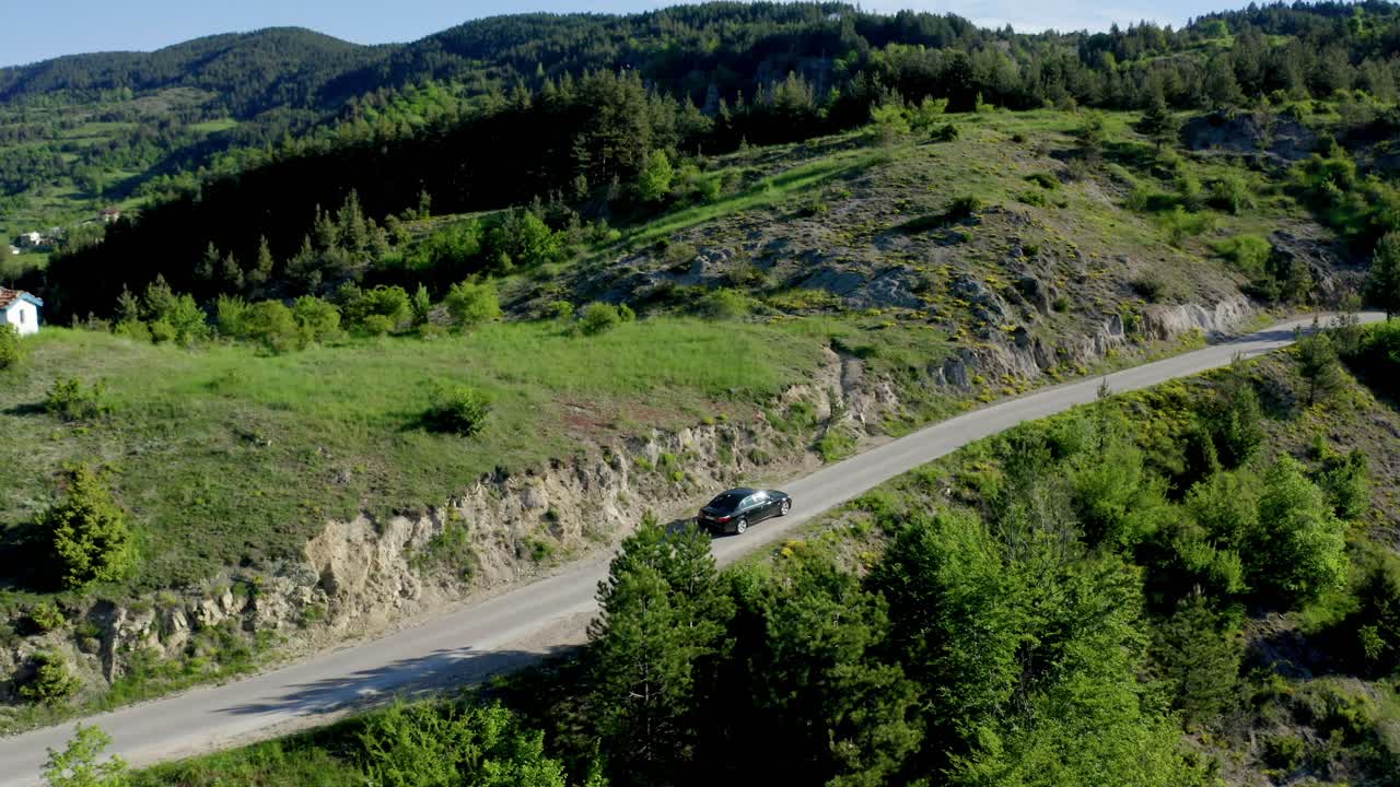drone siguiendo el disparo de un coche negro en una carretera de montaña durante un día soleado, bulgaria