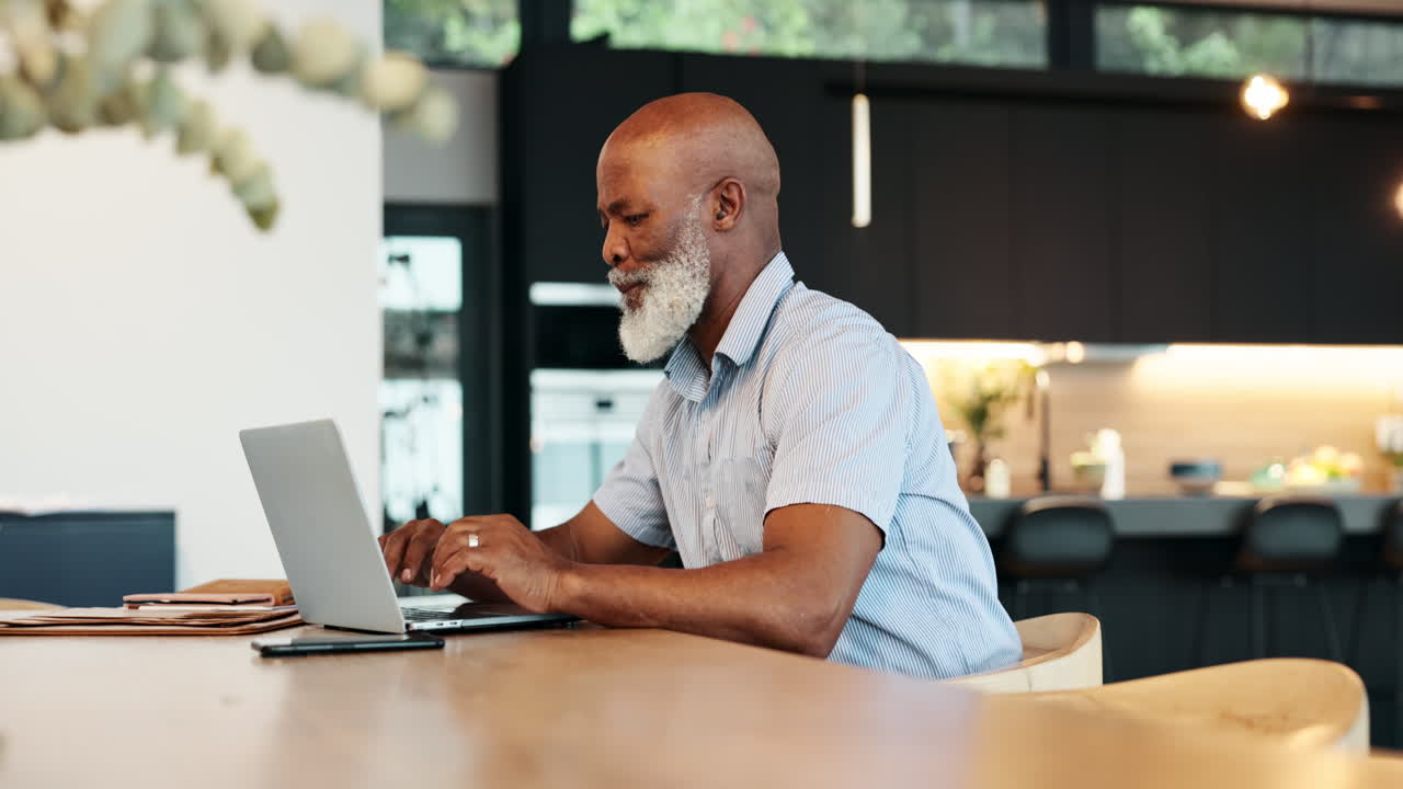 Senior man working on laptop in modern kitchen