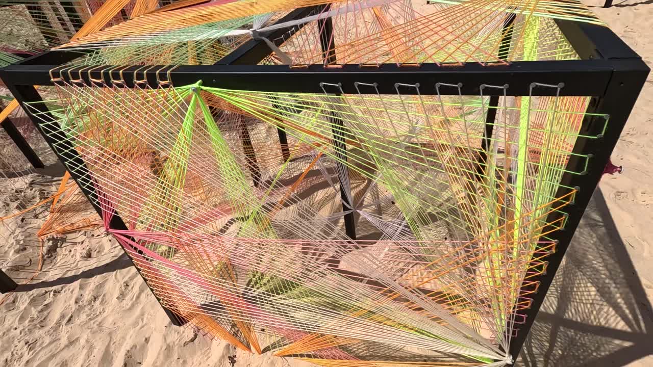 String art colorata all'interno di cubi di metallo su una spiaggia sabbiosa