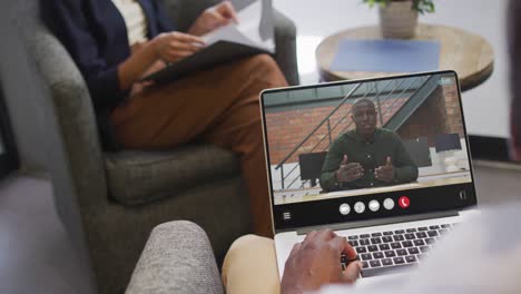 African-american-man-using-laptop-for-video-call,-with-business-colleague-on-screen