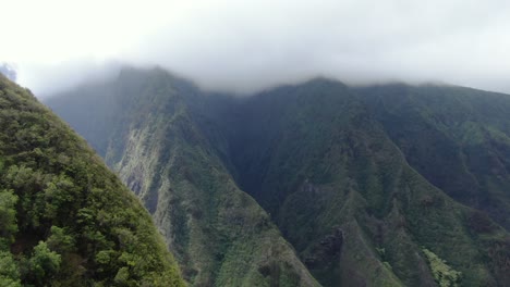 cinematic drone footage rising above the lush green mountain ridges of maui