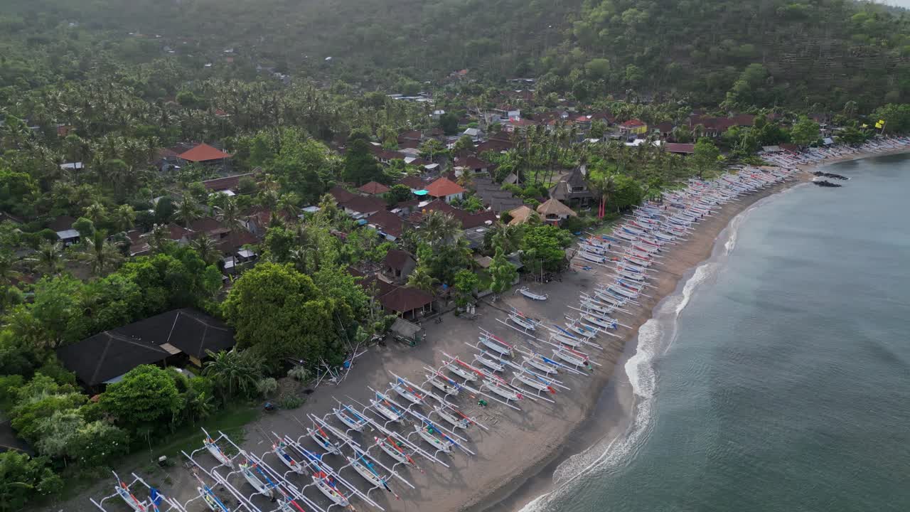 드론 도는 많은 전통적인 어선으로 줄지어 긴 해변 뒤에 작은 마을을 드러니다
