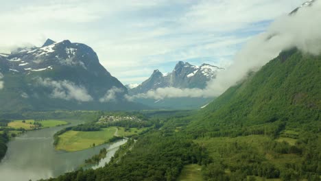 Idyllic-green-lush-valley-plains-with-winding-river-of-Andalsnes-off-the-Rauma-Line-in-Norway,-aerial-establish