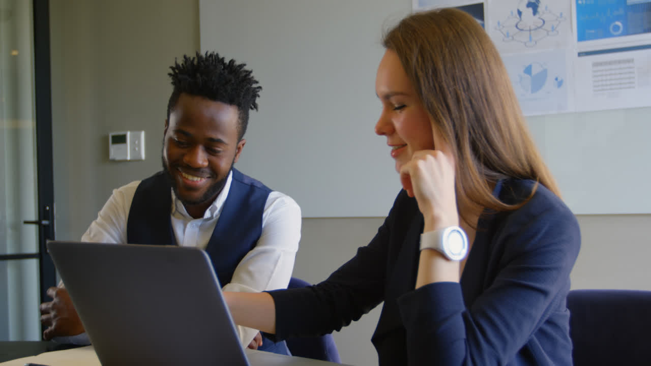 Side view of young cool mixed-race business team planning and sitting at table of modern office 4k