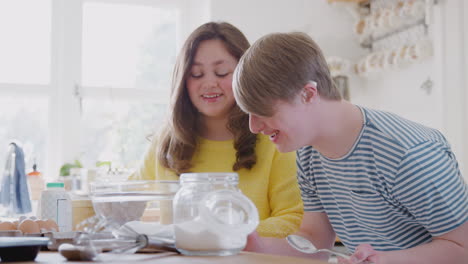 young downs syndrome couple measuring ingredients to bake cake in kitchen at home