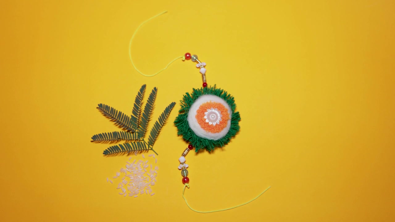 rakhi colorato fatto a mano con fili decorativi e sfondo giallo festivo