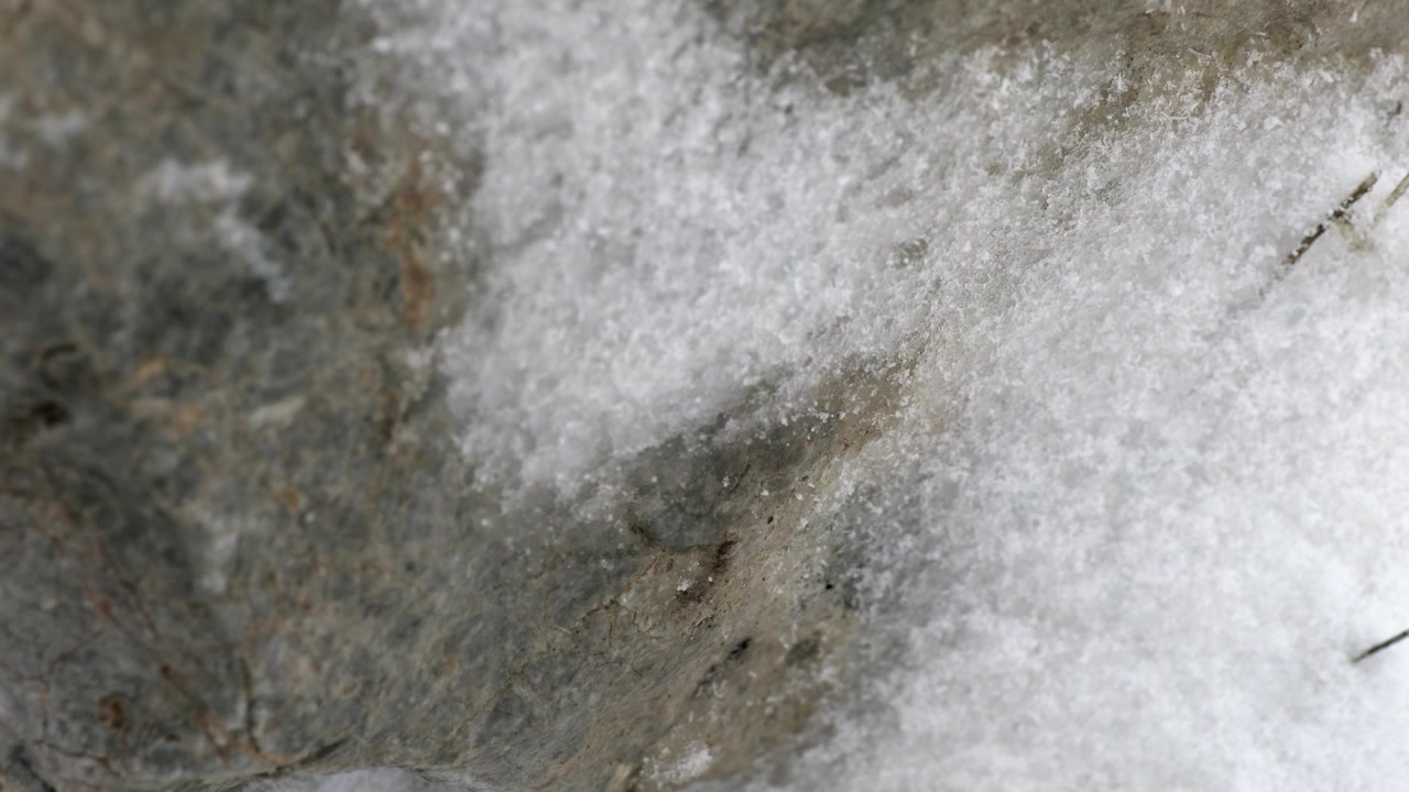 Primo piano di neve che cade su una superficie rocciosa ruvida