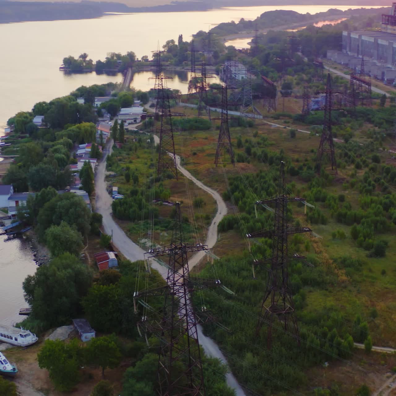 High-voltage power lines in nature. Transmission towers near the river. Electricity pylons tower at sunset. Energy efficiency concept.