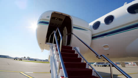 private jet with red carpet stairs on tarmac