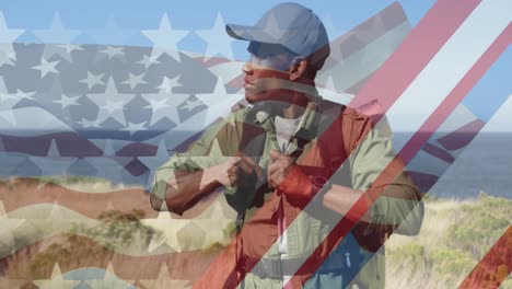 Animation-of-american-flag-over-african-american-man-hiking-in-mountains