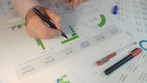 male hand is checking with marker list of business figures in the office