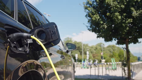 EV-car-with-a-plugged-charger-at-an-electric-vehicle-charging-point,-close-up