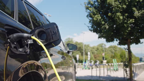 coche con un cargador enchufado en un punto de carga de vehículos eléctricos, de cerca