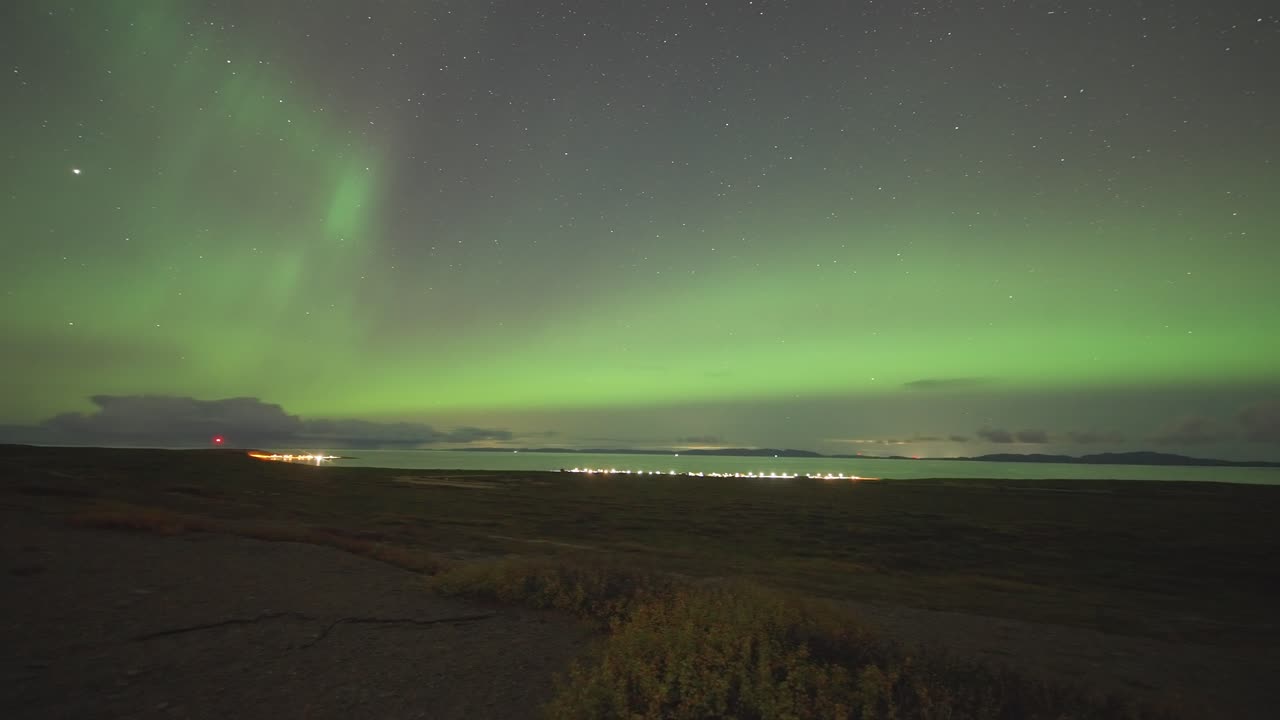 el cielo oscuro sobre el fiordo y la pequeña ciudad está adornada con una espectacular exhibición de las luces del norte