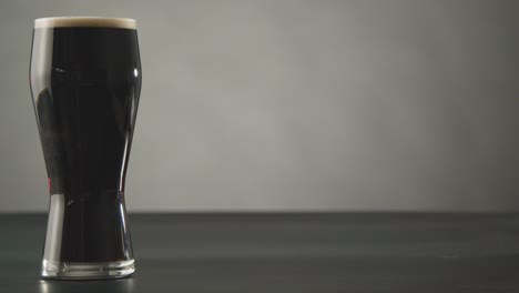 pint of irish stout in glass against studio background to celebrate st patricks day