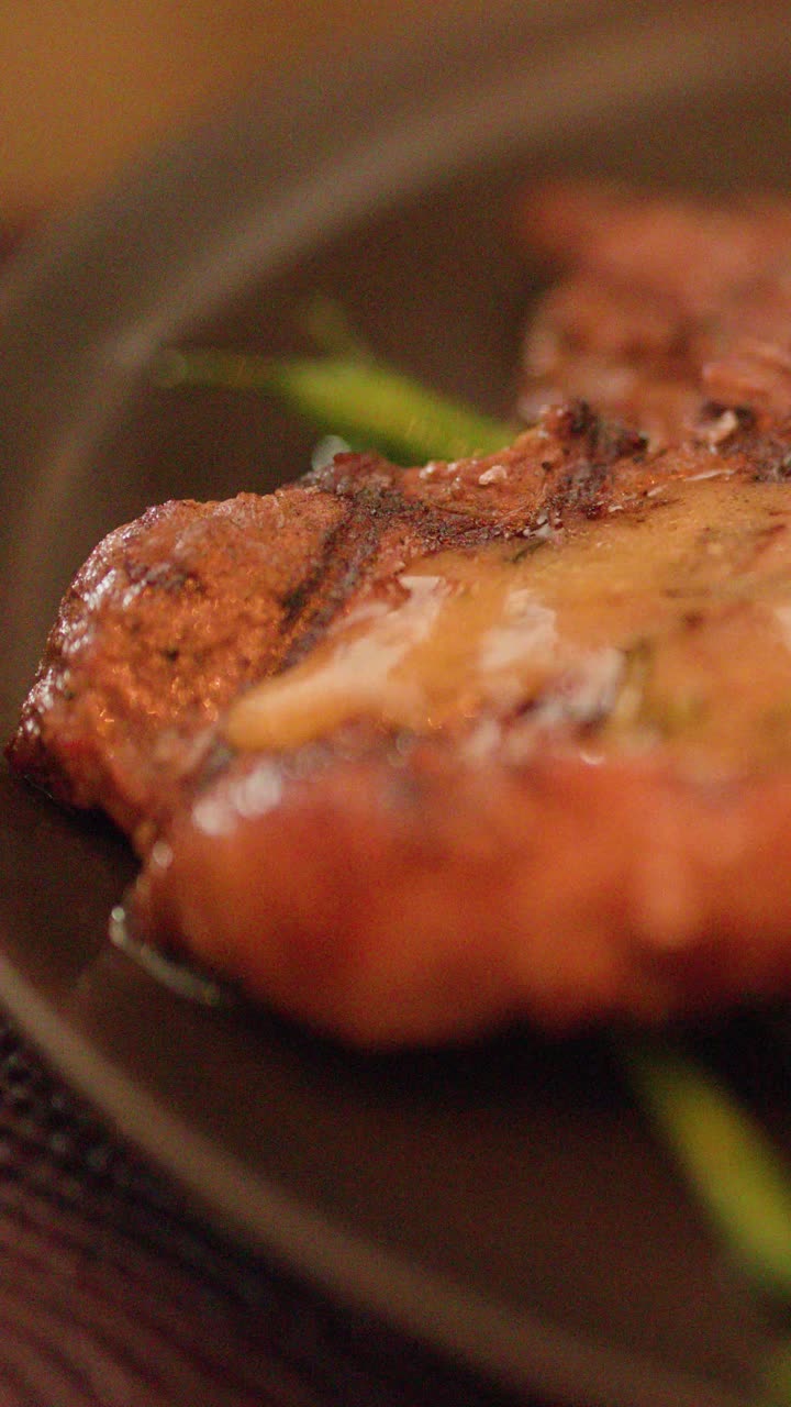 Primo piano di burro che si scioglie su una bistecca alla griglia, illuminazione calda, messa a fuoco selettiva, atmosfera da cena elegante.