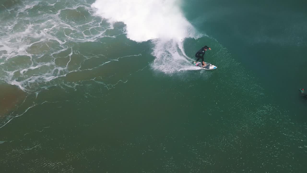 Surfista professionista che cavalca un'onda lunga in Sud America, Perù - Ripresa aerea con drone in tracking.