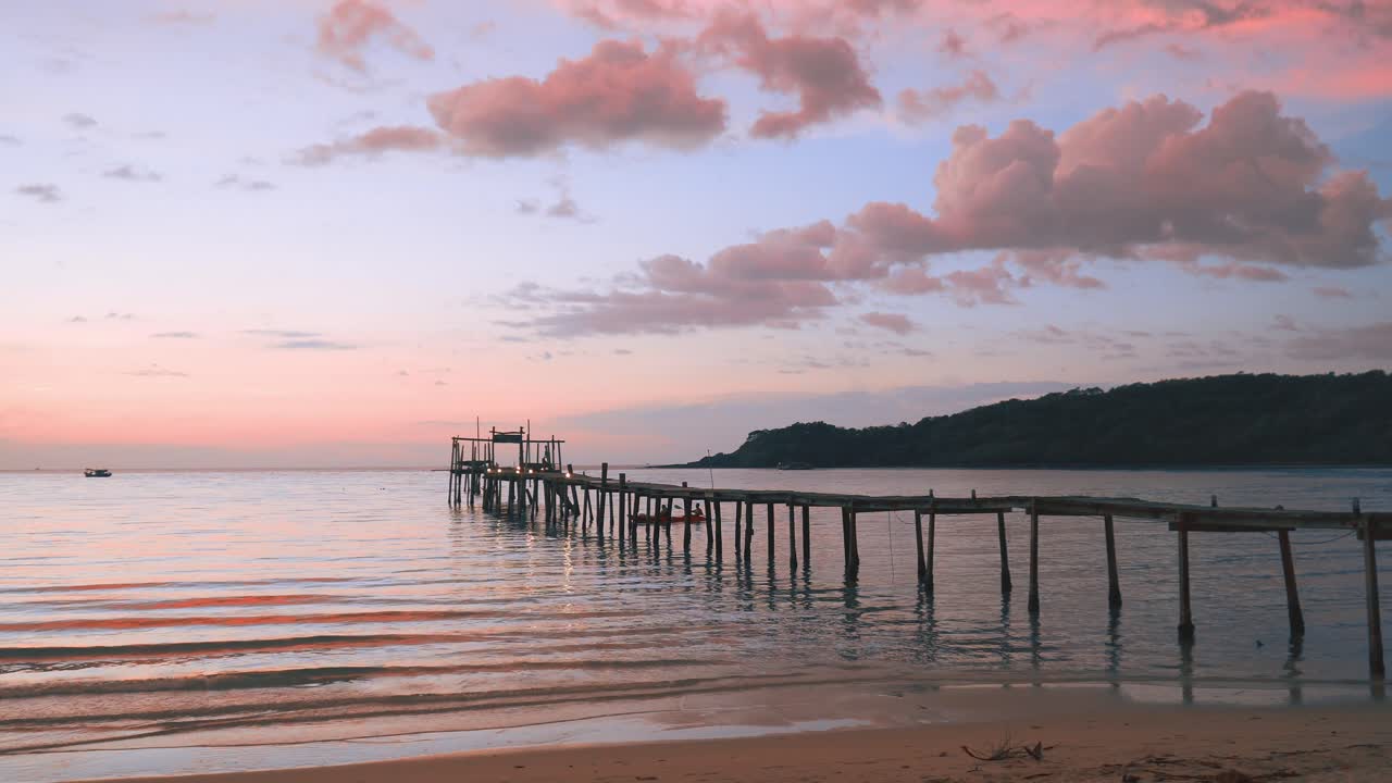 Peaceful Sunset at a Tropical Beach with a Wooden Pier Extending Into the Ocean