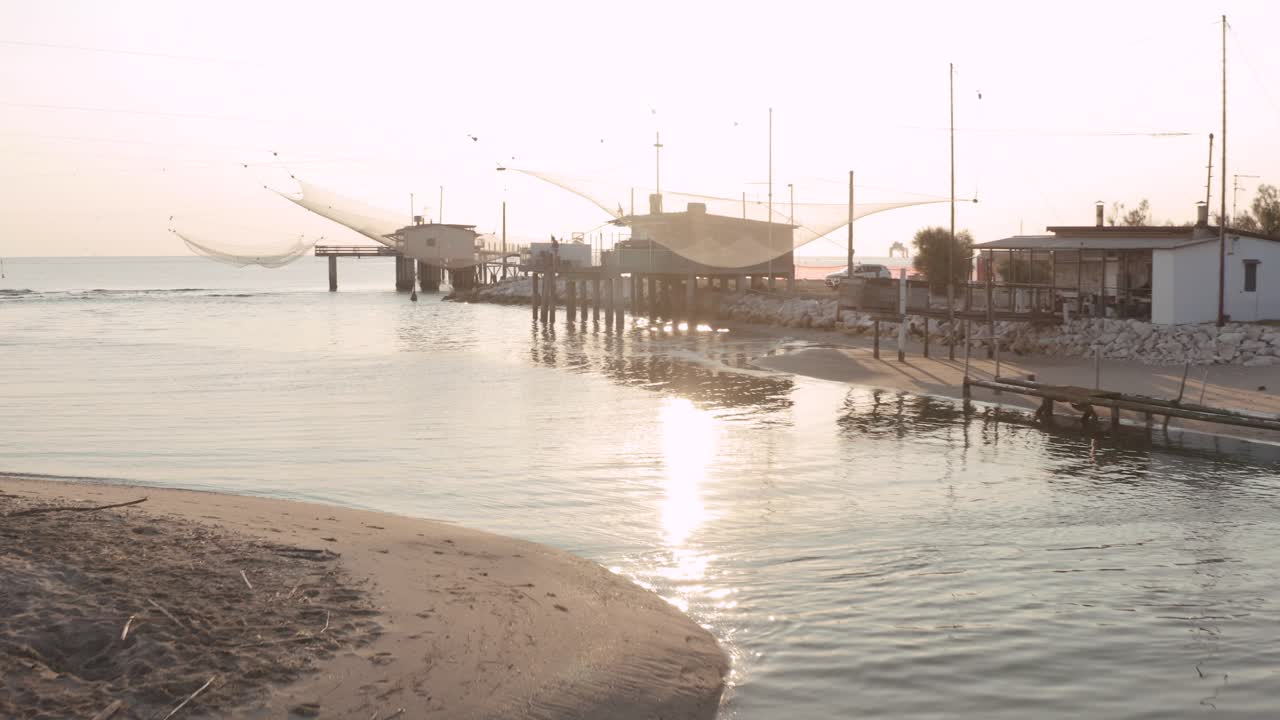 paisaje de cabañas de pesca en el río al amanecer con la típica máquina de pesca italiana, llamada ""trabucco"",lido di dante, fiumi uniti ravenna cerca del valle de comacchio