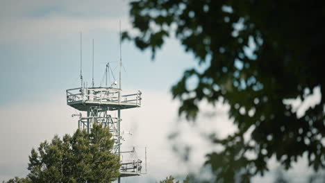 A-radio-tower-on-Trdinov-vrh,-looking-at-it-through-the-branches-of-the-tree