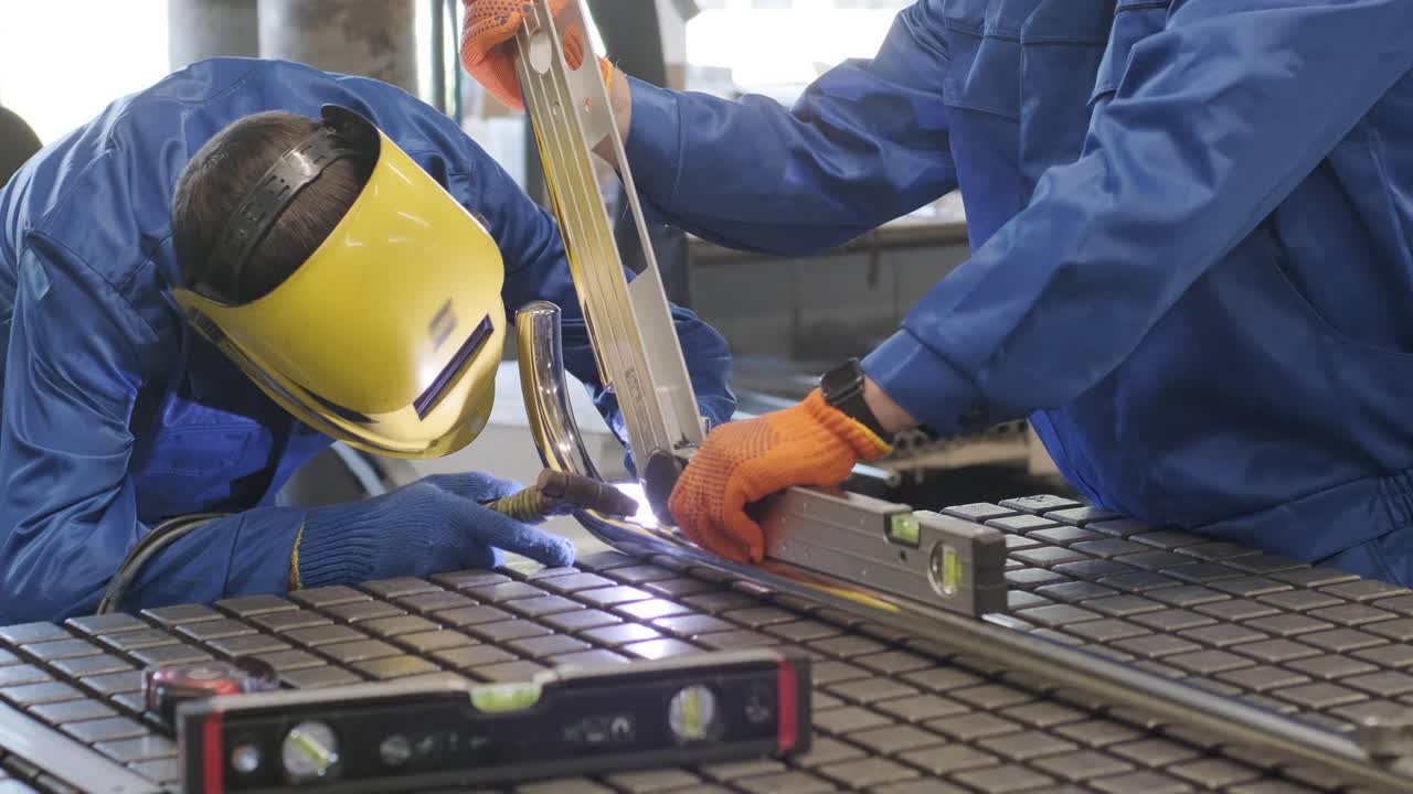 primer plano de un hombre que usa una máscara de soldadura en un taller. los trabajadores del metal usan mano de obra manual. soldador calificado. soldador está soldando las tuberías de acero inoxidable en la fábrica. soldador de piezas automotoras industriales en la fábrica