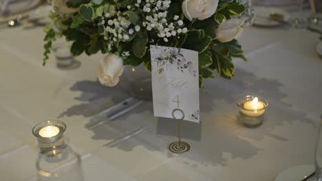 Centro-De-Flores-Con-Tarjeta-De-Asignación-De-Mesa-En-El-Banquete-De-Boda