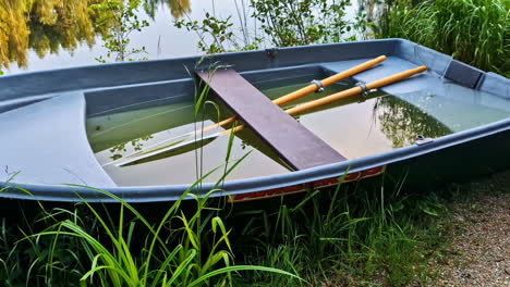 water slowly filling into a rowboat floating on a calm green pond