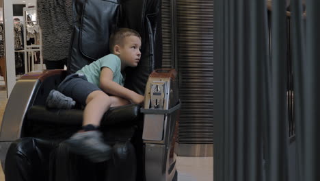 a bored boy in a massage chair in the mall