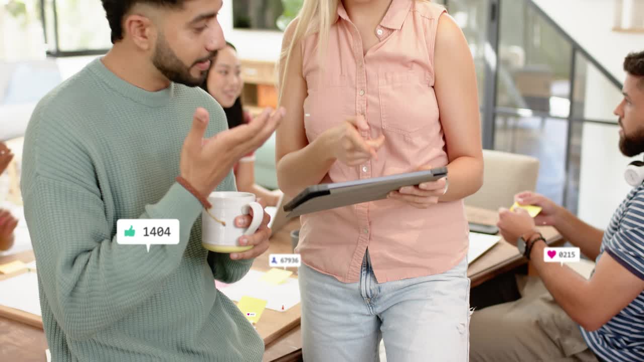 Marketing pair collaborating, woman tapping tablet adding likes while man with mug tracking ROI