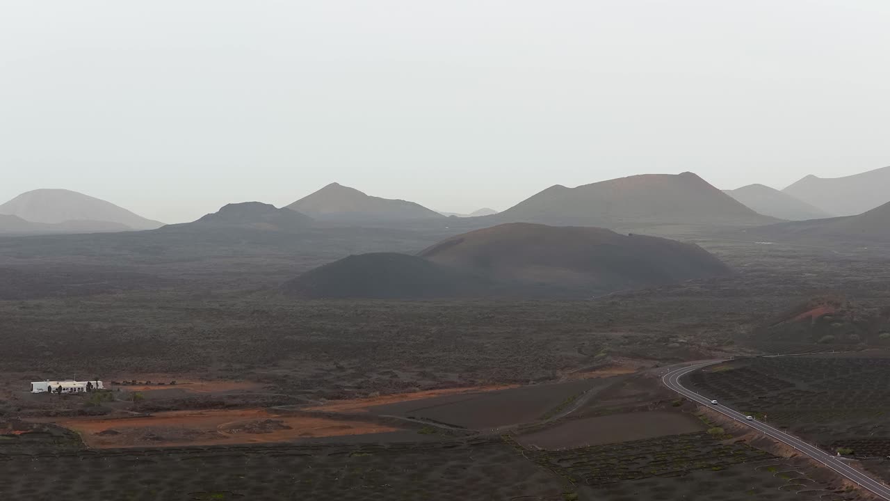 Hazy Vineyard Landscape Of La Geria In Lanzarote, Spain, Backdropped By Volcanic Hills In Daytime. wide aerial shot