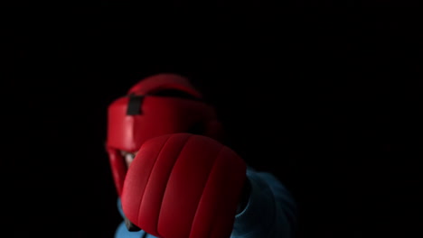 sporty young man boxing on black background