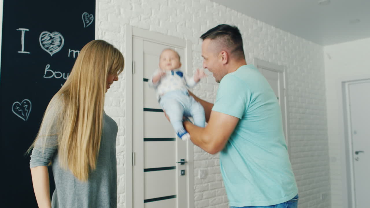 Happy Young Father Playing With His Son Two Months In Their Own House Mom Looks At Them A Strong And