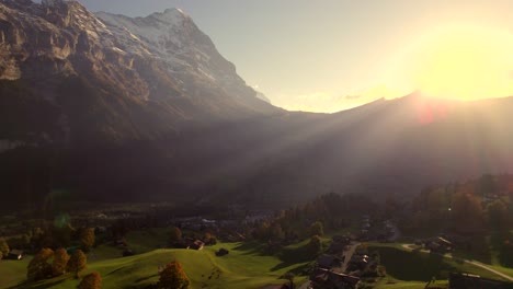 aerial drone footage rising down and pushing in towards grindewald village and eiger north face in stunning sunset light