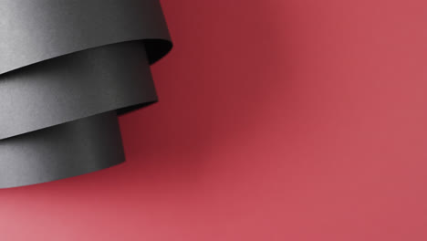 Close-up-of-rolls-of-black-paper-and-copy-space-on-red-background