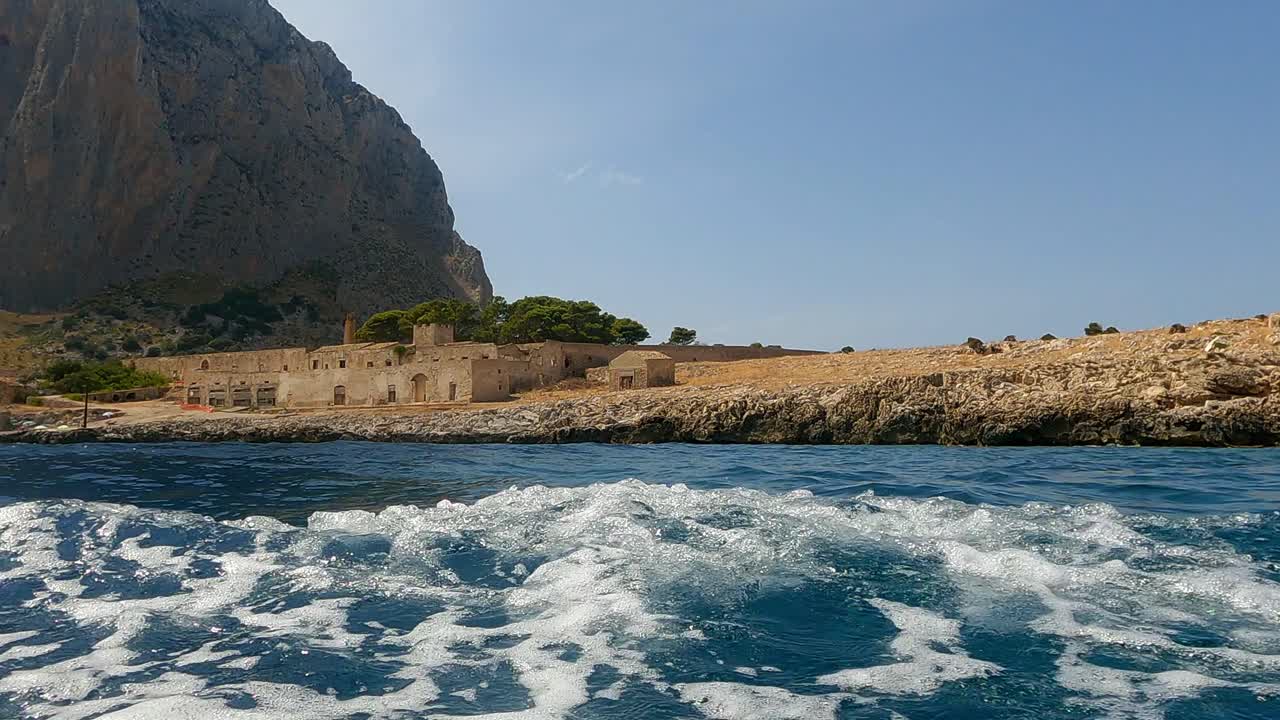 Old Sicilian seafront Tonnara Del Secco used for tuna fishing as seen from boat in Sicily