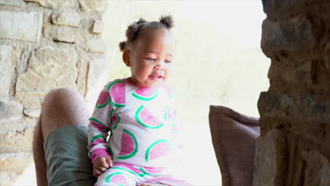 south african baby sitting on her dad with cute pyjamas paying games and doing a fist bump