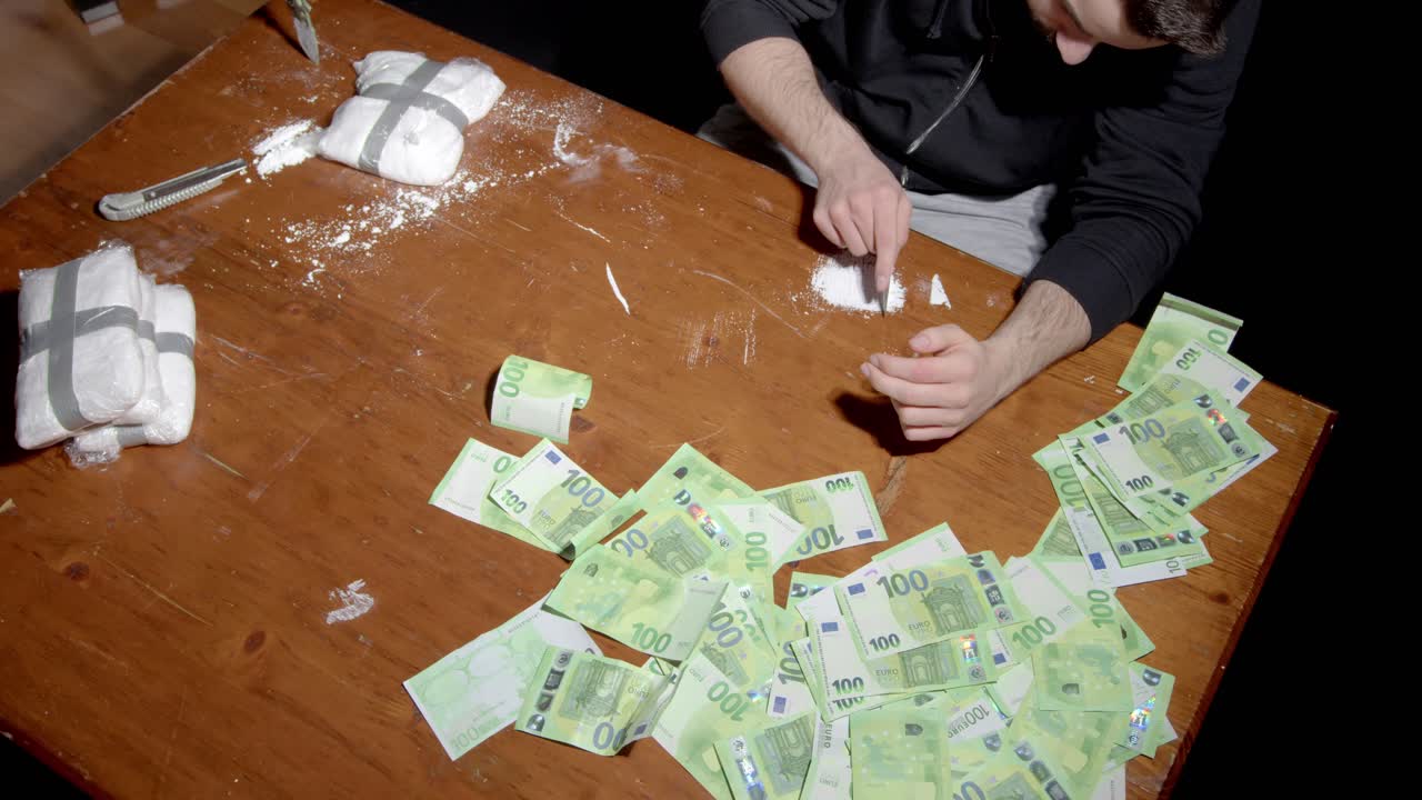 Persona con sostanze stupefacenti e banconote sul tavolo