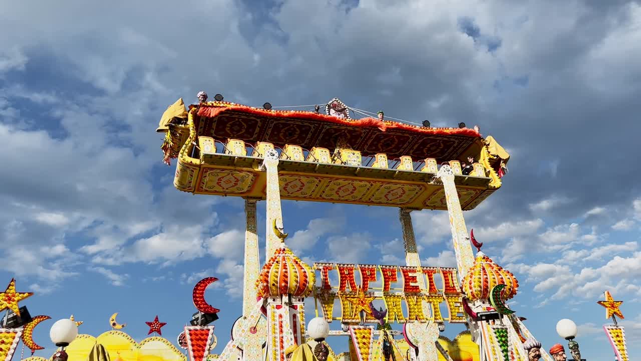 Flying carpet attraction at amusement park moving with child on board