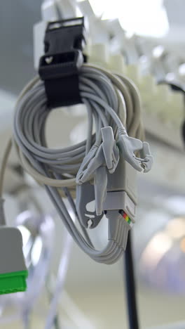 white wires from equipment hanging near the stethoscope in operational theatre. low angle view. blurred backdrop. vertical video