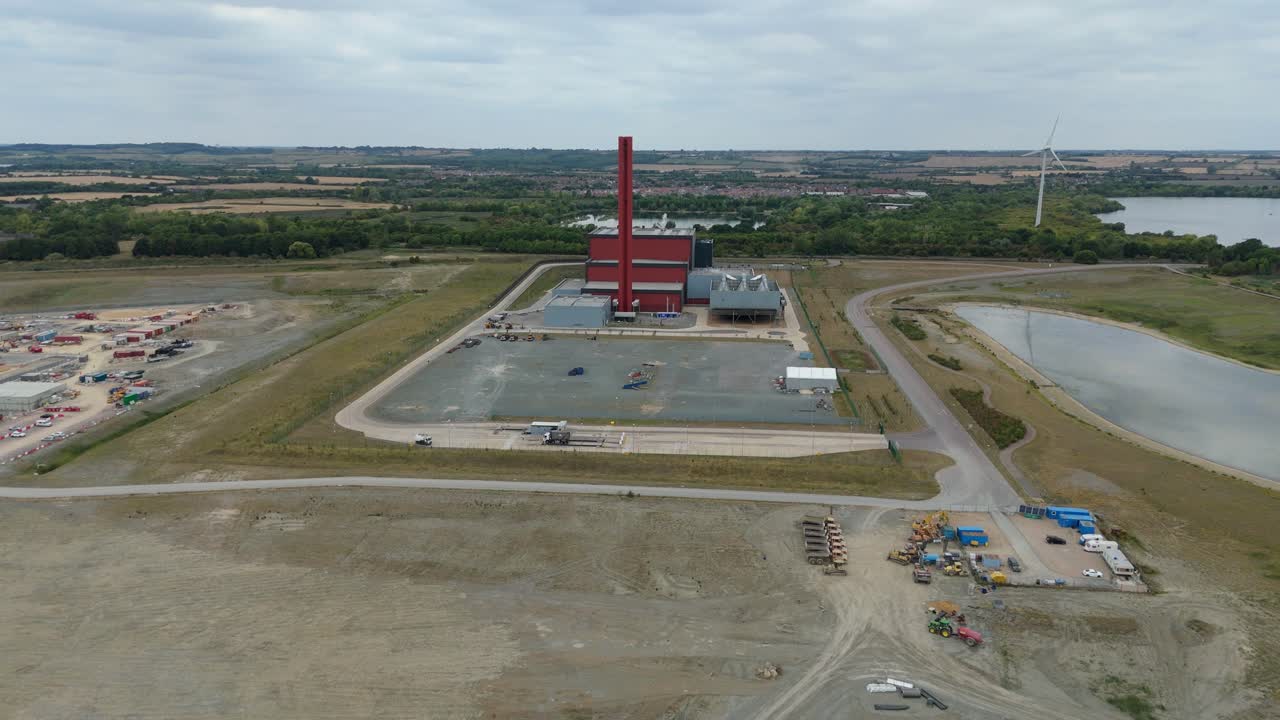 Aerial drone footage of Bedford England power plant showing industrial chimney stacks and fossil fuel energy production with electricity infrastructure