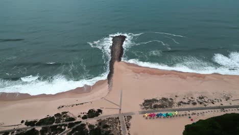 Aerial-view-of-the-ocean-reaching-the-shore-in-a-moody-day-with-nice-waves-and-colors