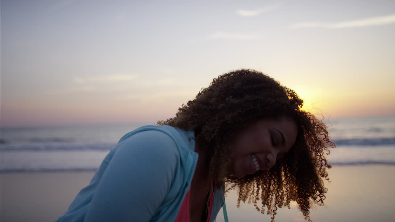mujer étnica bailando en la playa con teléfono inteligente