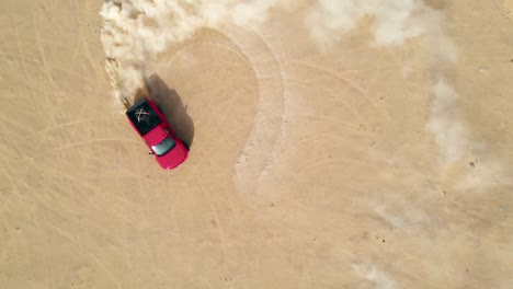 Red-truck-drifting-in-the-desert-sand,-aerial-top-view