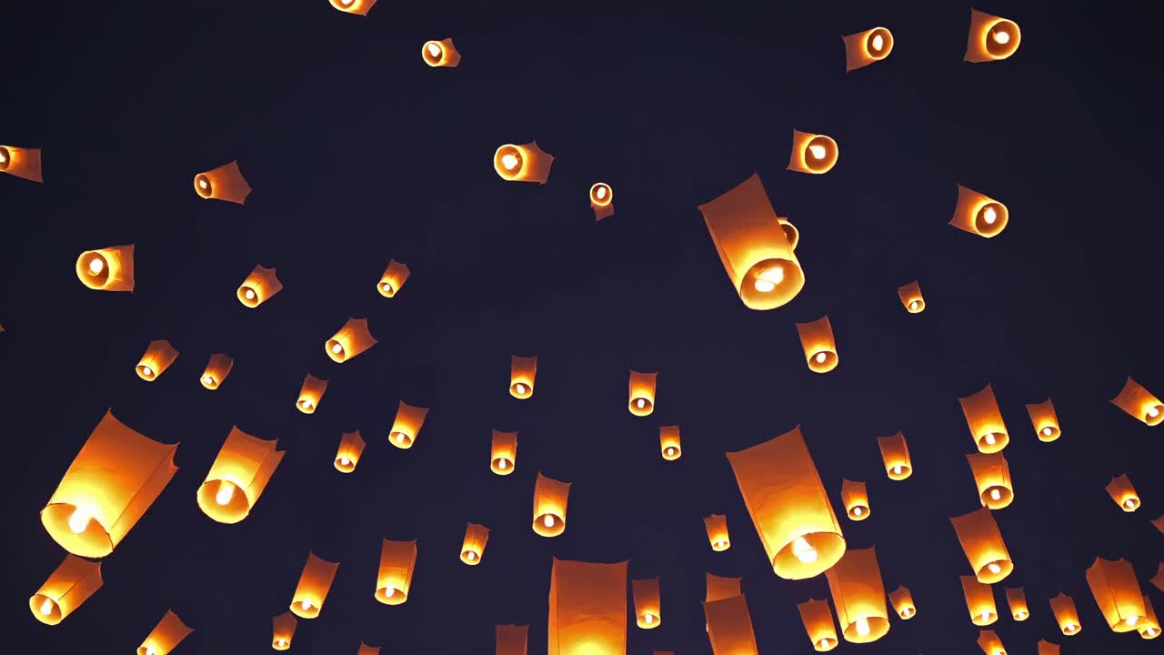 A mesmerizing video scene of glowing lanterns floating against a dark sky, captured from a low-angle